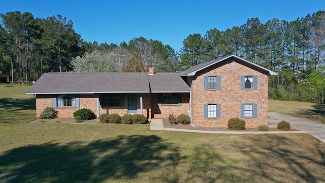 tri-level home featuring a front lawn, covered porch, brick siding, and a chimney