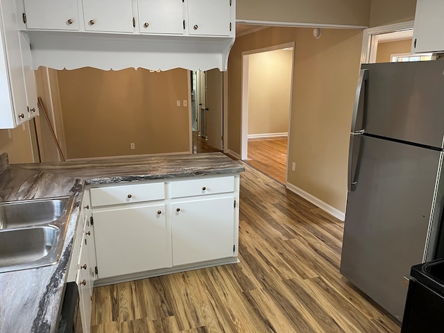 105 Martinson Dr, Abbeville, AL 36310 - kitchen with freestanding refrigerator, white cabinetry, and wood finished floors
