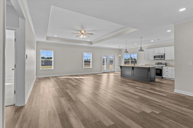 unfurnished living room with hardwood / wood-style flooring, ornamental molding, and a tray ceiling