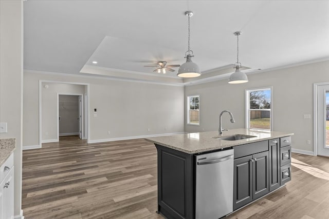 kitchen with pendant lighting, an island with sink, sink, stainless steel dishwasher, and a raised ceiling