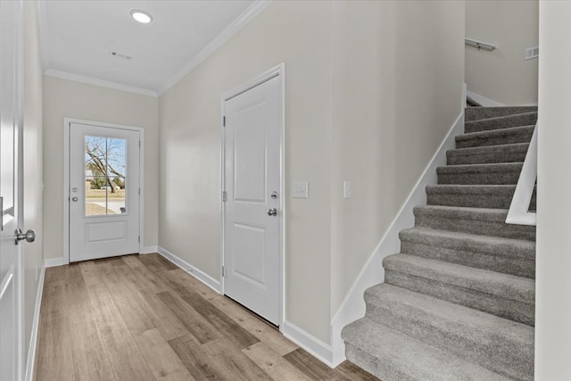 foyer with crown molding and light hardwood / wood-style floors