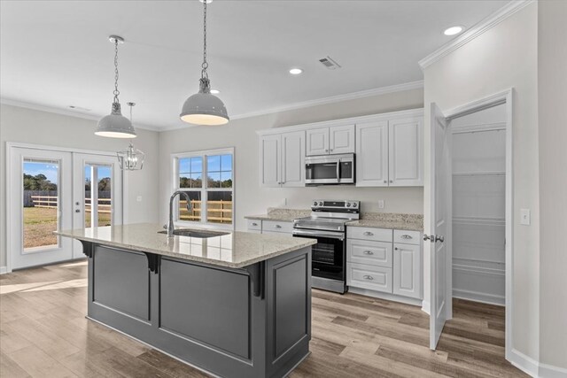 kitchen with a kitchen island with sink, white cabinets, sink, ornamental molding, and dark hardwood / wood-style flooring