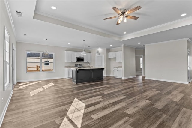 unfurnished living room featuring sink, a tray ceiling, wood-type flooring, and ceiling fan