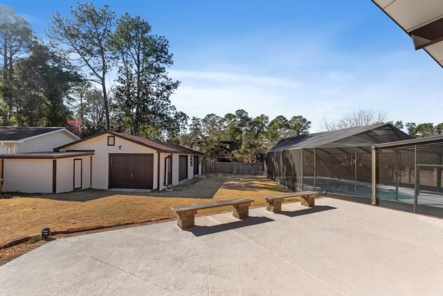 view of patio featuring a lanai, an outdoor structure, and a garage