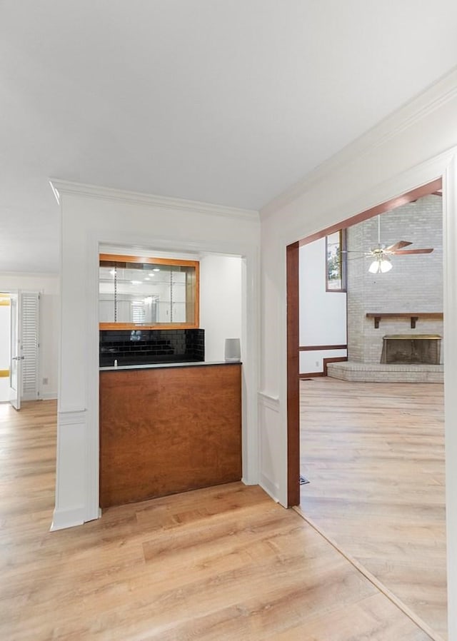 kitchen with a brick fireplace, light hardwood / wood-style flooring, and crown molding