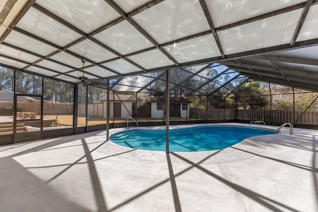 view of pool featuring glass enclosure, a patio area, and a storage shed