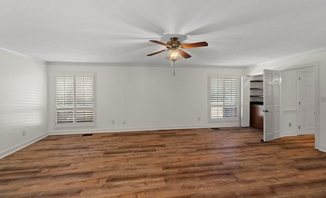 spare room with a wealth of natural light, dark wood-type flooring, and ornamental molding