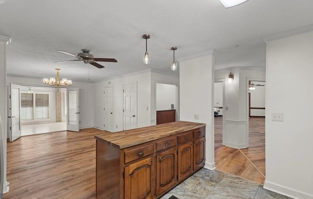 kitchen with wooden counters, ceiling fan with notable chandelier, decorative light fixtures, and ornamental molding