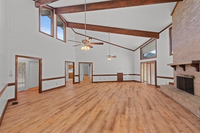 unfurnished living room with beamed ceiling, light wood-type flooring, high vaulted ceiling, and a brick fireplace