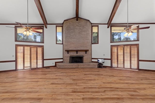 unfurnished living room featuring beamed ceiling, light wood-type flooring, a fireplace, and high vaulted ceiling