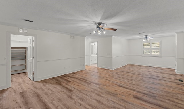 spare room featuring crown molding, a textured ceiling, and light wood-type flooring