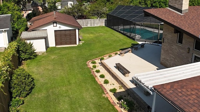 exterior space featuring glass enclosure, a patio area, an outbuilding, and a garage