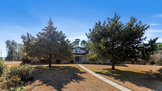 view of property hidden behind natural elements with a front yard