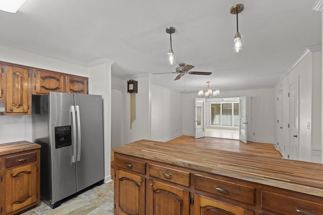 kitchen featuring butcher block countertops, stainless steel fridge, pendant lighting, and ceiling fan with notable chandelier