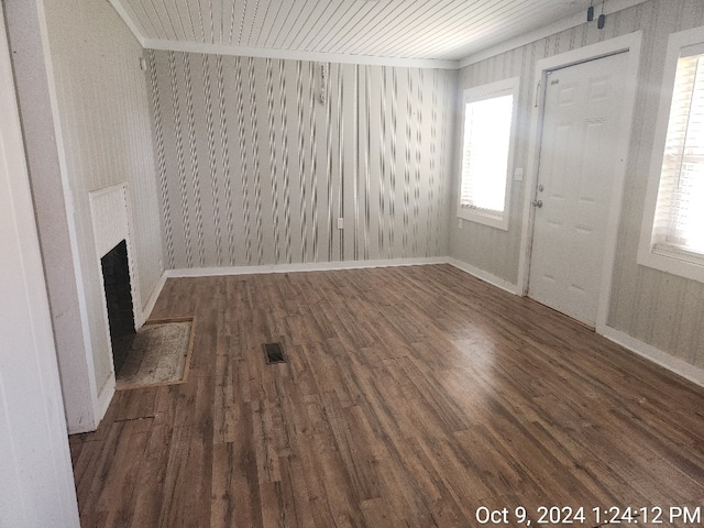 unfurnished living room with dark wood-type flooring, a healthy amount of sunlight, and a brick fireplace