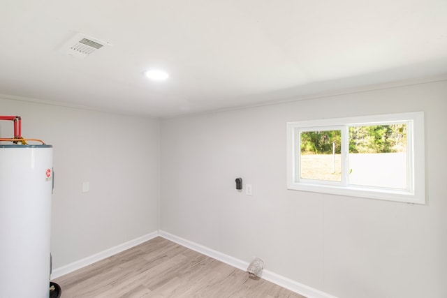 laundry room featuring water heater, light hardwood / wood-style floors, and hookup for an electric dryer