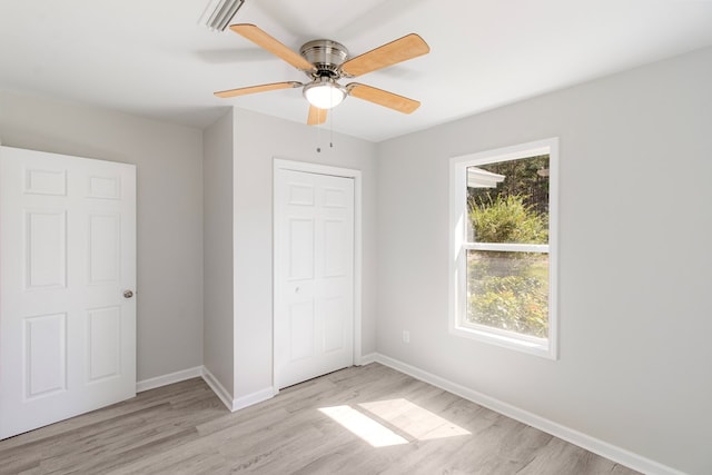 unfurnished bedroom with ceiling fan, light wood-type flooring, and a closet