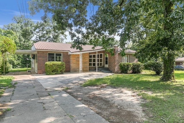 1105 Deborah St, Dothan, AL 36301 - view of front of property with a front yard, a metal roof, driveway, brick siding, and an attached carport