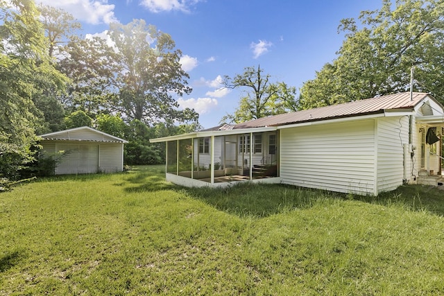 1105 Deborah St, Dothan, AL 36301 - back of house featuring a sunroom, a garage, a lawn, a metal roof, and an outbuilding