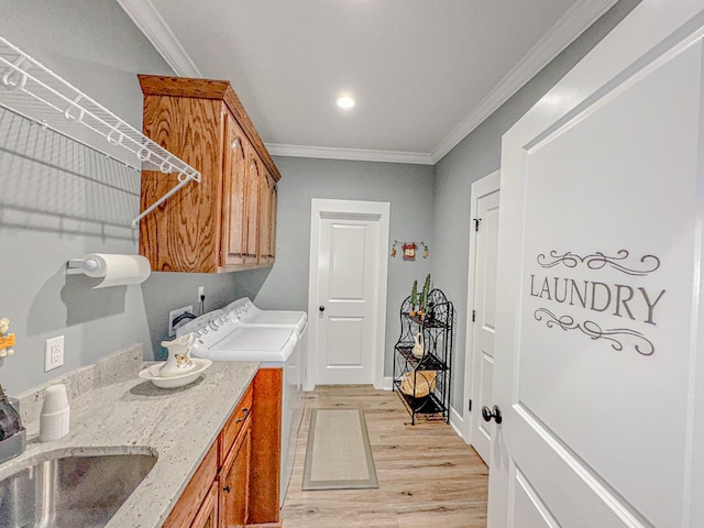 laundry room with cabinets, ornamental molding, sink, washing machine and dryer, and light hardwood / wood-style floors