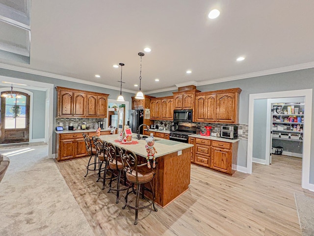 kitchen featuring decorative backsplash, stainless steel appliances, crown molding, light hardwood / wood-style flooring, and an island with sink