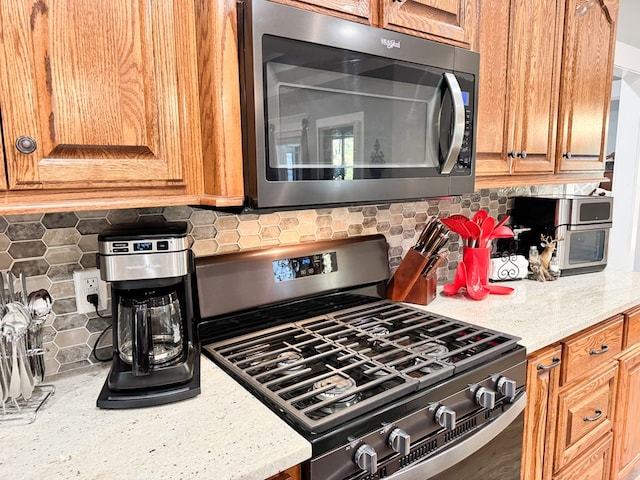 kitchen with decorative backsplash, light stone countertops, and appliances with stainless steel finishes