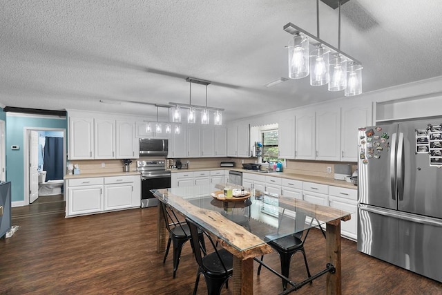 6970 Walden Dr, Kinsey, AL 36303 - kitchen with stainless steel appliances, light countertops, white cabinets, dark wood-type flooring, and a textured ceiling