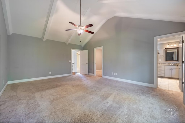 unfurnished bedroom with ceiling fan, sink, high vaulted ceiling, ensuite bathroom, and light carpet