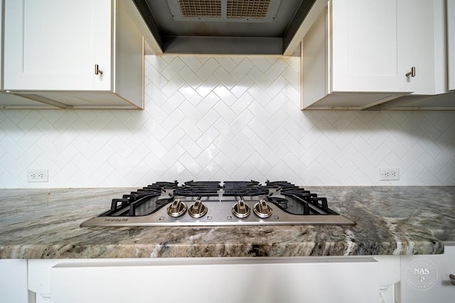 kitchen featuring tasteful backsplash, dark stone counters, extractor fan, stainless steel gas stovetop, and white cabinets