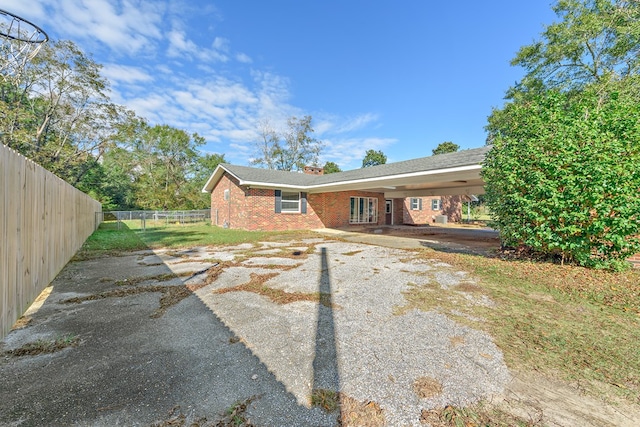 1303 Highland Dr, Elba, AL 36323 - rear view of house with brick siding, a chimney, and an attached carport