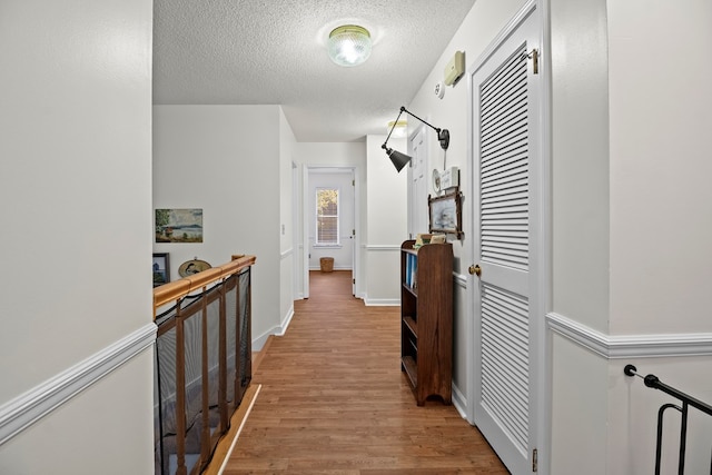 hallway featuring light hardwood / wood-style flooring and a textured ceiling