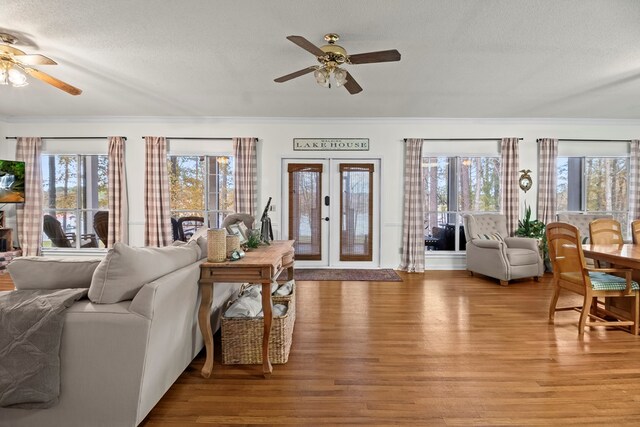 living room with a textured ceiling, light wood-type flooring, a wealth of natural light, and ceiling fan