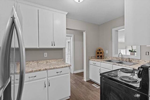 1301 S Bell St, Dothan, AL 36301 - kitchen with freestanding refrigerator, a sink, black range with electric stovetop, dark wood-type flooring, and white cabinetry