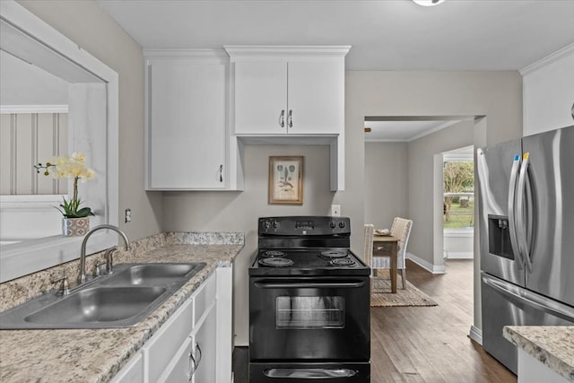 1301 S Bell St, Dothan, AL 36301 - kitchen with stainless steel fridge, black electric range oven, a sink, wood finished floors, and light countertops