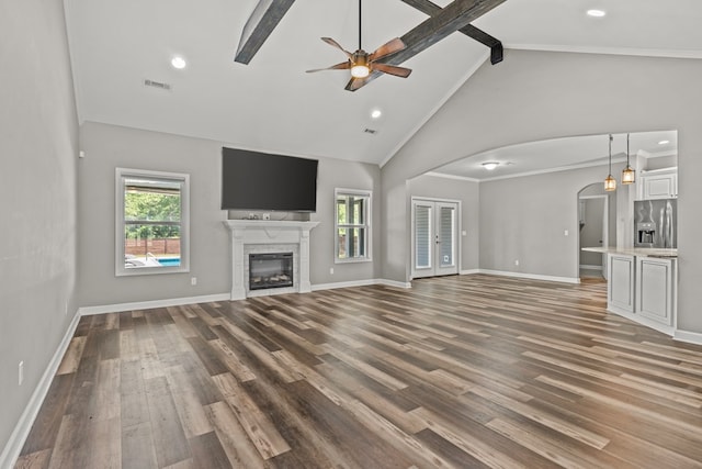 unfurnished living room with wood finished floors, visible vents, arched walkways, beamed ceiling, and ceiling fan