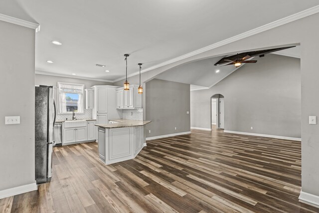 kitchen with arched walkways, freestanding refrigerator, white cabinets, dark wood-style flooring, and recessed lighting
