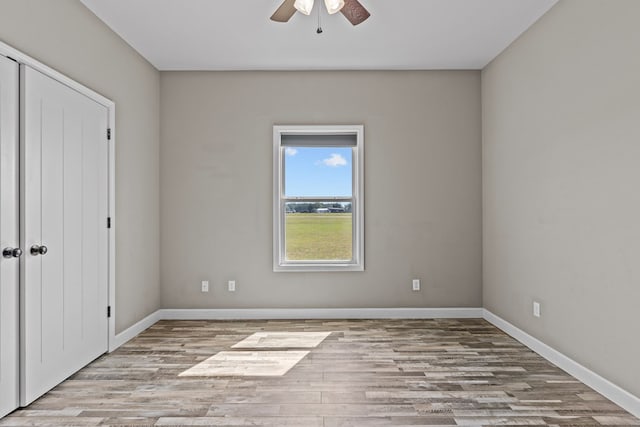 unfurnished bedroom with wood finished floors, a closet, baseboards, and ceiling fan