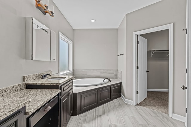 bathroom featuring a bath, a walk in closet, and vanity