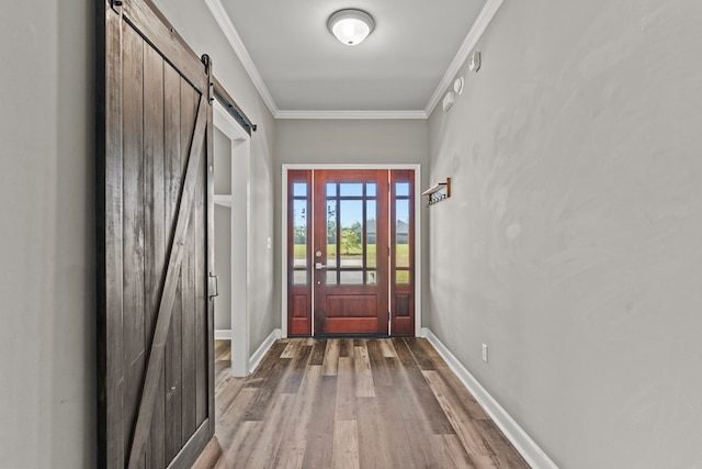 doorway to outside featuring a barn door, wood finished floors, baseboards, and ornamental molding