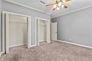 unfurnished bedroom featuring carpet floors, ornamental molding, two closets, and baseboards