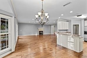 kitchen with recessed lighting, a fireplace, visible vents, white cabinetry, and open floor plan