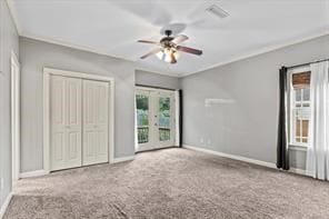 unfurnished bedroom featuring carpet, crown molding, visible vents, a ceiling fan, and baseboards