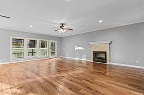 unfurnished living room with ceiling fan, a fireplace, baseboards, and wood finished floors