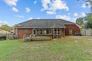 back of property featuring a yard, fence, and a wooden deck