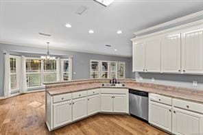 kitchen featuring recessed lighting, a peninsula, wood finished floors, a sink, and dishwasher