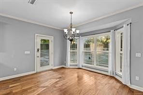 unfurnished dining area featuring plenty of natural light, crown molding, baseboards, and wood finished floors