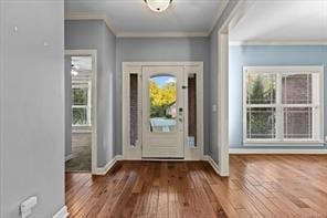 foyer entrance with ornamental molding, wood-type flooring, and baseboards