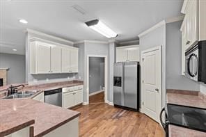 kitchen featuring crown molding, stainless steel appliances, light wood-style floors, and white cabinets