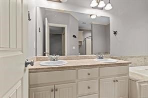 full bathroom featuring a bathtub, a sink, and double vanity