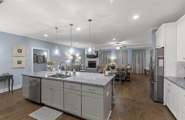 kitchen featuring stainless steel appliances, sink, ceiling fan, hanging light fixtures, and a center island with sink